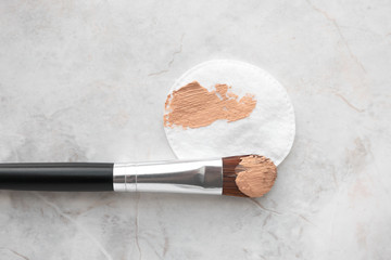 Make up brush and cotton round with BB cream or foundation on luxury marble background, top view. Daily makeup