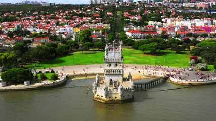 Wall Mural - Lisbon, Portugal. Aerial view of Belem Tower in Lisbon, Portugal during the cloudy day. Famous buildings with crowd of tourists, zoom out