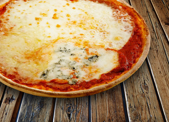 Pizza quatro formaggi on a textured wooden table