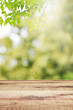 Wooden table and blurred green leaves nature bokeh background. 