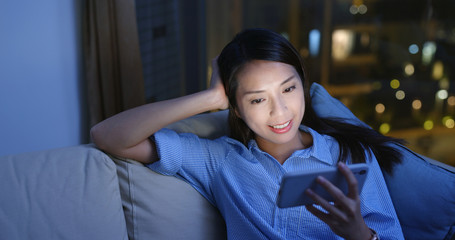 Canvas Print - Woman watch at cellphone and sit on sofa in the evening