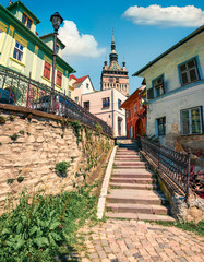 Splendid morning view of famous medieval fortified city and the Clock Tower built by Saxons. Sunny summer cityscape of Sighisoara, Transylvania, Romania, Europe. Traveling concept background.