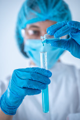 Chemist woman holding test tube with fluid, making laboratory research