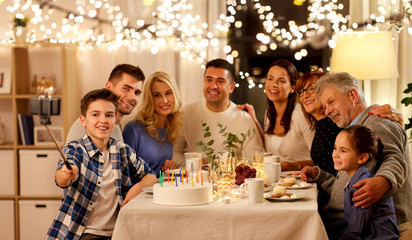 celebration, holidays and people concept - happy family having birthday tea party at home and taking picture by smartphone on selfie stick