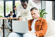 © LIGHTFIELD STUDIOS - african american businessman with coffee to go looking at laptop in hands of colleague