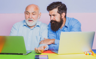 Two businessman sitting at the table typing on laptop computer working with new business plan. Two businessmen. Office workers.