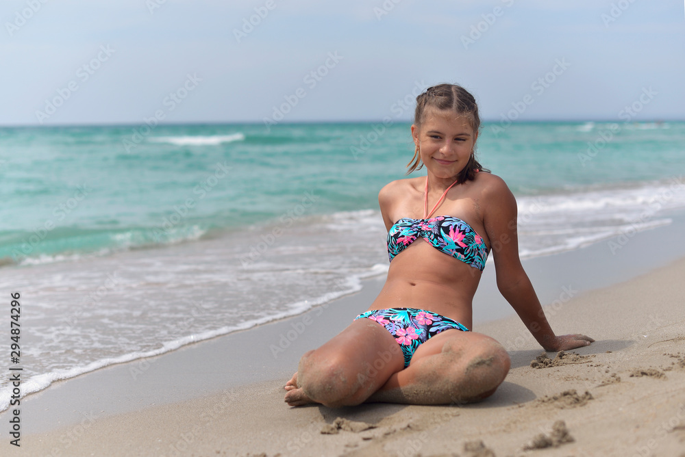 Teenage girl lying on the sandy beach on a hot summer day - obrazy, fototapety, plakaty 