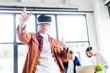 © LIGHTFIELD STUDIOS - young businessman using vr headset while multicultural colleagues working in office