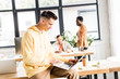 © LIGHTFIELD STUDIOS - young businessman using laptop while sitting on desk in office near multicultural colleagues