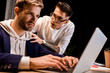 © LIGHTFIELD STUDIOS - young businessman touching shoulder of colleague working on laptop at night in office
