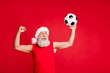 © deagreez - Portrait of crazy santa claus in nicholas hat cap screaming yes raising fists see goal in match wearing sports wear isolated over red background