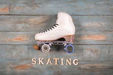 Wall Mural - artistic roller skates on a wood background with skating word formed with white letters