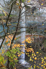 Wall Mural - large waterfall with high cliffs and trees with autumn foliage