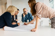 © FOLIO - Businesspeople looking at plans during meeting