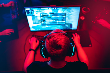 Professional cyber gamer studio room with personal computer armchair, keyboard for stream in neon color blur background. Soft focus