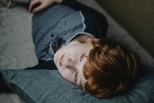 Portrait Of Daydreaming Boy Lying On Couch Looking At Distance