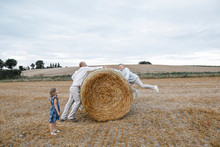 Father And His Children Playing On Hay Bales