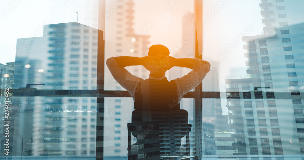 Portrait of relaxed businessman in modern office.Business young man relax after work of office window with business district view. - obrazy, fototapety, plakaty 