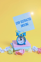 Wall Mural - Text sign showing Stop Distracted Driving. Business photo showcasing asking to be careful behind wheel drive slowly Alarm clock sticky note paper balls stacked notepads colored background