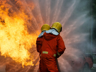 Wall Mural - firefighter spray water to fire burning car workshop fire training