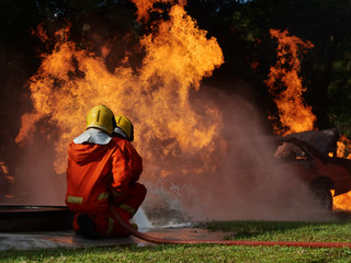 Wall Mural - firefighter spray water to fire burning car workshop fire training