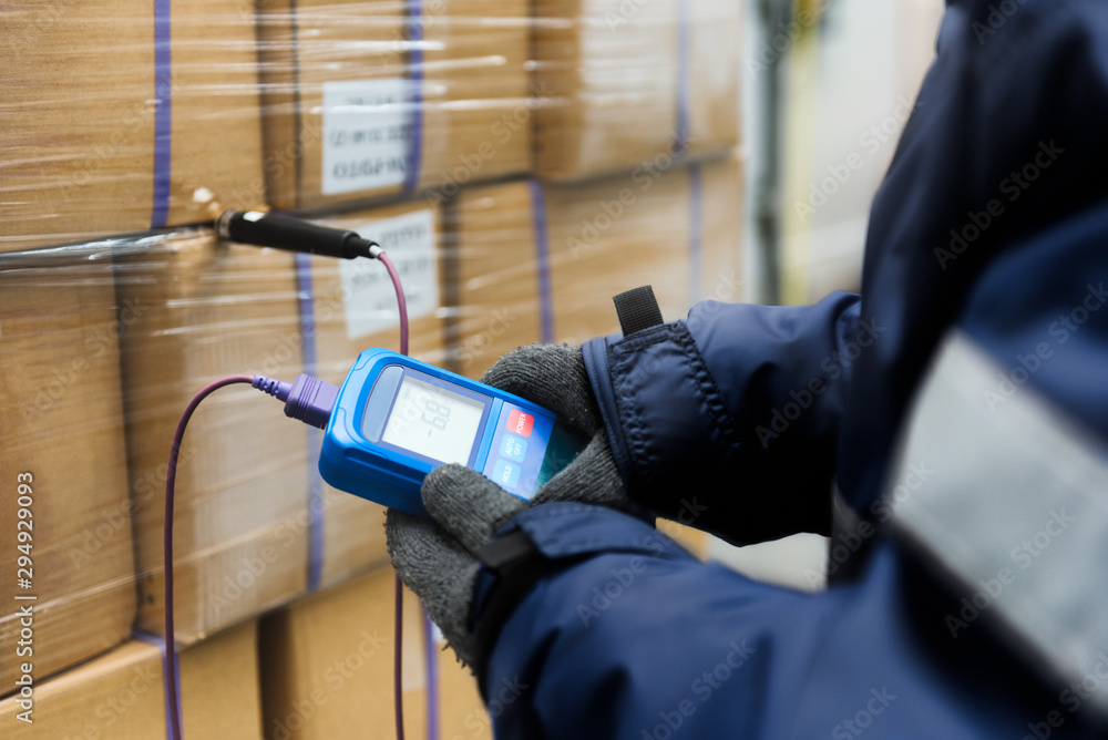 Hand of worker using thermometer to temperature measurement in the goods boxes with ready meals after import in the cold room or warehouse for keep temperature room - obrazy, fototapety, plakaty 