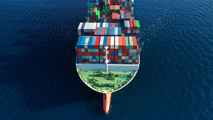 Aerial drone photo of Container cargo Ship carrying load in truck-size colourful containers cruising in deep blue Mediterranean sea 