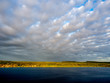 Horizon of stratocumulus clouds over golden land and dark blue sea