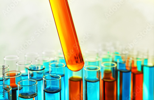 Photographie Taking test tube with liquid sample on color background, closeup
