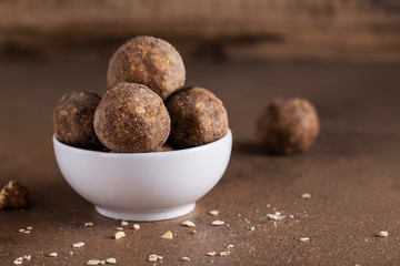 energy balls in a white Cup on a brown table peanut butter dates walnuts oatmeal