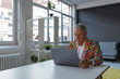 © Westend61 - Senior businessman wearing colorful sports jacket using laptop