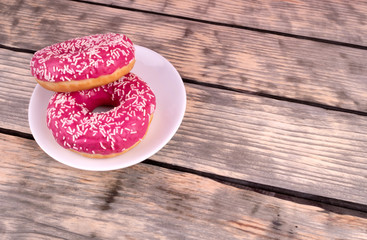 donuts are depicted on a white background. one is covered with pink icing and two on the sides of chocolate, decorated with powder.