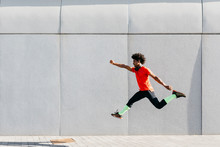 Young Man Doing Jumps With A Gray Wall In The Background