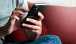 Frau Jugendliche Teenager mit Handy smartphone beim posten, chaten, tippen und schreiben in social media zuhause auf dem Sofa mit mobile phone eine Nachricht tippen.