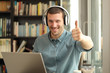 © Antonioguillem - Happy adult man with laptop and headphones with thumbs up