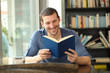 © Antonioguillem - Happy reader reading a paper book in a coffee shop