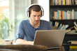 © Antonioguillem - Adult man wearing headphones using a laptop
