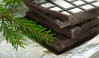 Bars of chocolate and fir branch on white paper