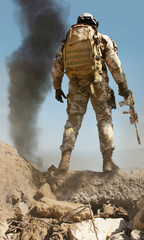 Desert soldier back posing on stone mountain battleground.