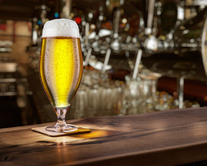 Frosty glass of light beer on the bar counter.