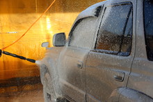 Spraying Of White Shampoo On The Half Side Surface Of Brutal Jeep Gray Silver 4x4 Vehicle From A Foam Gun At The Car Wash