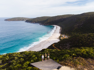 Wall Mural - Group of travellers watching the sunset over a beach in Albany, Australia. Beautiful remote beach down below the three travellers. Shot aerially from a drone.