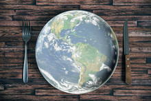The Planet Earth Plate With A Fork And Knife On A Wooden Background. World Hunger Concept. Feed The World.