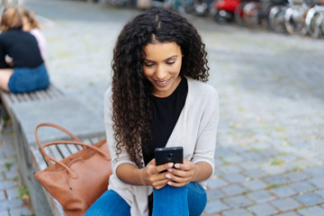 Young trendy woman in jeans relaxing on a bench