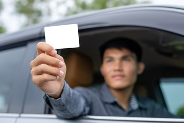 Young asian man sitting in the modern car and holding blank of white card