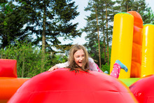 Happy Little Girl Having Lots Of Fun On A Inflate Castle While Jumping.