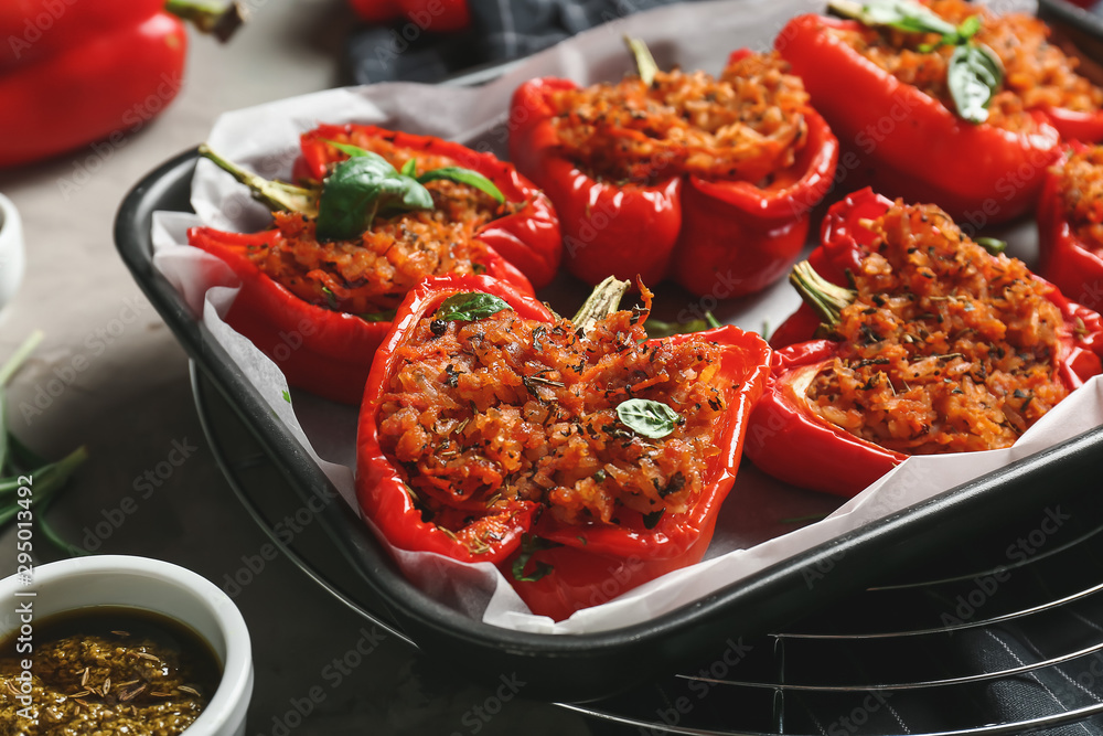 Baking dish with tasty stuffed pepper and sauce on table - obrazy, fototapety, plakaty 