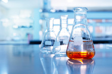 Orange Solution In Science Glass Flask In Blue Chemistry School Laboratory Background