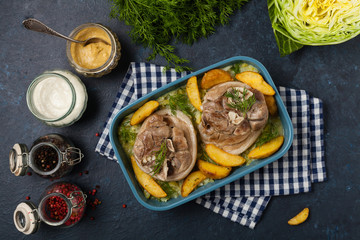 Wall Mural - Boiled knuckle, served with cabbage and baked potatoes. Top view. Darkblue background. Dark mod.