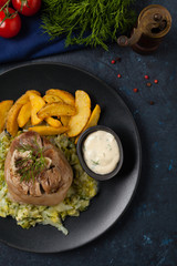 Wall Mural - Boiled knuckle, served with cabbage and baked potatoes. Top view. Darkblue background. Dark mod.